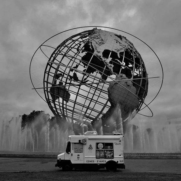 Darkened black and white photograph of ice cream truck in front of world sculpture