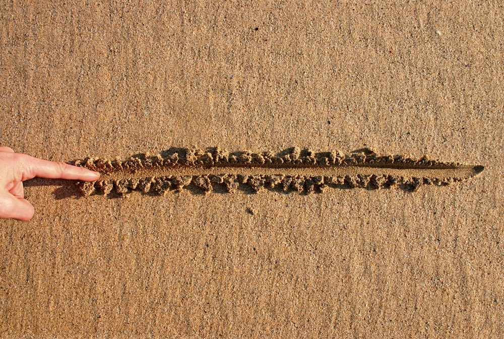 Finger Drawing A Straight Line In The Sand