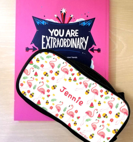 A Pencil-Pal pencil case in flamingo print, personalised with the name Jennie, sitting on top of a book called You Are Extraordinary