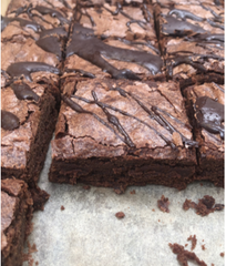 Tray of freshly cut decadent brownies drizzled with chocolate 