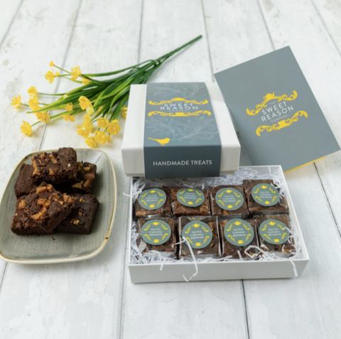 beautiful box of The Sweet Reason Company brownies surrounded by flowers and a plate of unwrapped brownies 