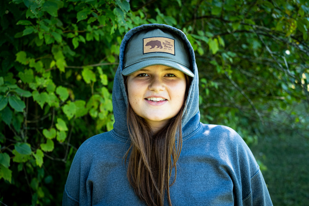 Cute girl wearing a baseball cap that says The Brown Bear