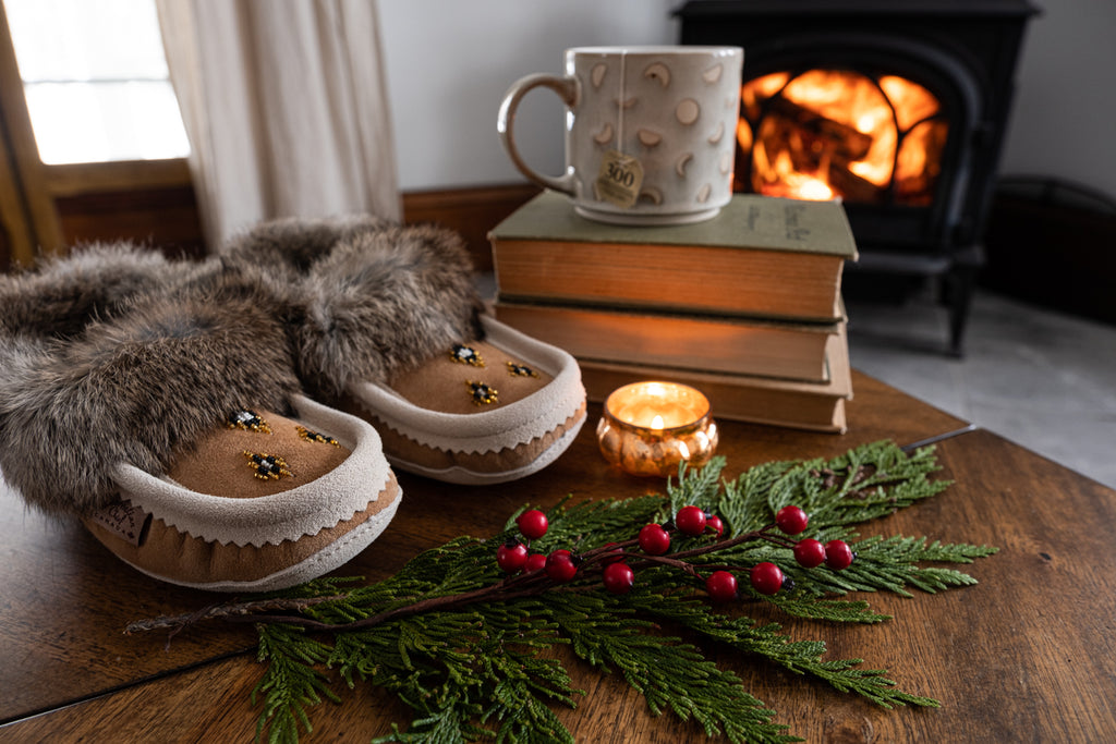 combination of cozy moccasin slippers, mug, novels, roaring fire and candle