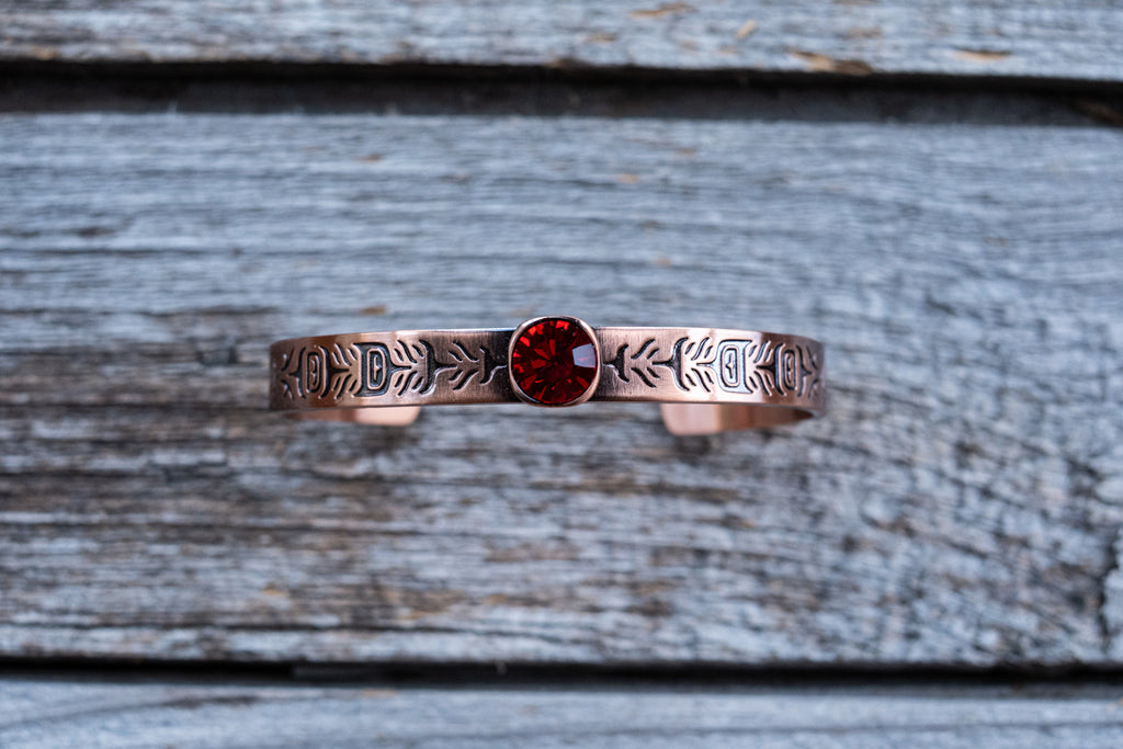 open cuff copper bangle with Indigenous art engraving ruby-coloured crystal