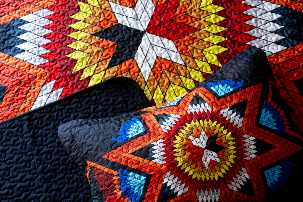Characterized by vivid starbursts of red, orange, yellow, and blue on a black background, the stunning Indigenous Eight-Point Star Quilt comes with two matching pillowcases