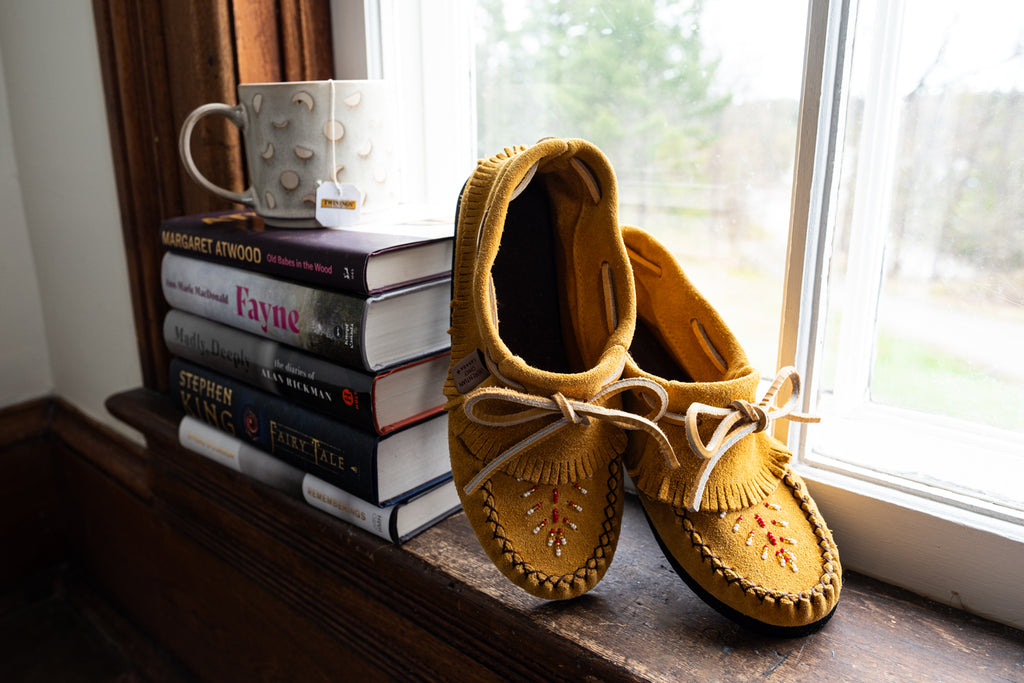 handmade authentic moccasins next to a stack of the best books