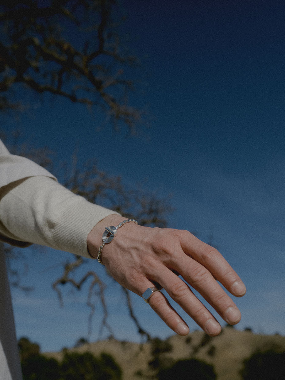 model wearing eight bracelet and cushion ring in silver