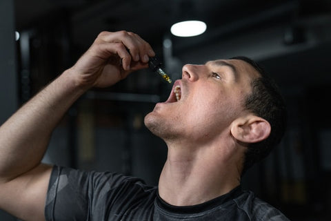 A man dropping CBD oil into his mouth using a pipette. 