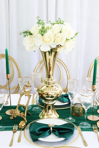 Gold cutlery on a white table on a with green accents - wedding celebration