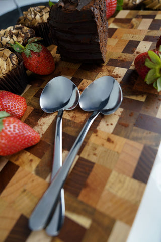 Two heart dessert spoons on a wooden chopping board
