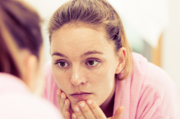 Woman looking at her face in a mirror. 