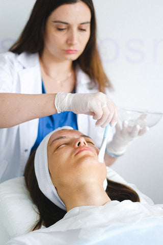 beautician applying mask to woman’s face