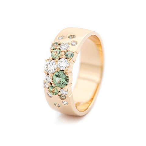 Asymmetrically placed light green sapphires and white tw/vs diamonds in a 6mm wide Keto meadow ring made in 18K yellow gold. Design by Jussi Louesalmi, Au3 Goldsmiths.
