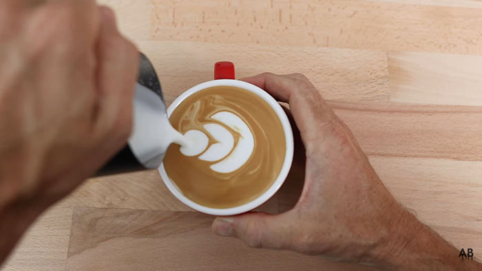 pour milk into coffee