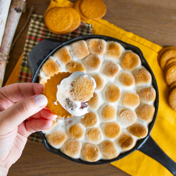 Dewey's Triple Ginger Moravian Cookie Thins scooping up S'mores dip from a cast iron pan