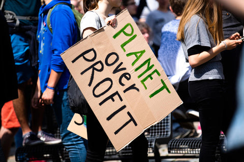 Woman at protest holding sign that states planet over profit