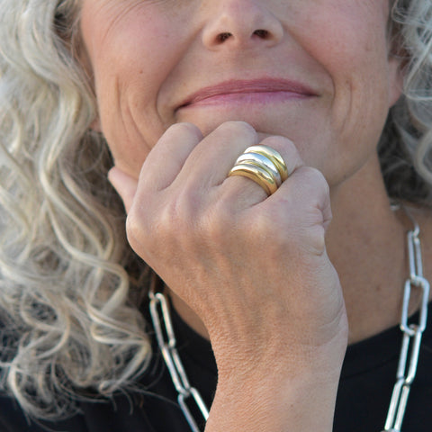 A photo of a model wearing our signature minimalist ring stack with the hand carved ring in sterling silver and 18k gold