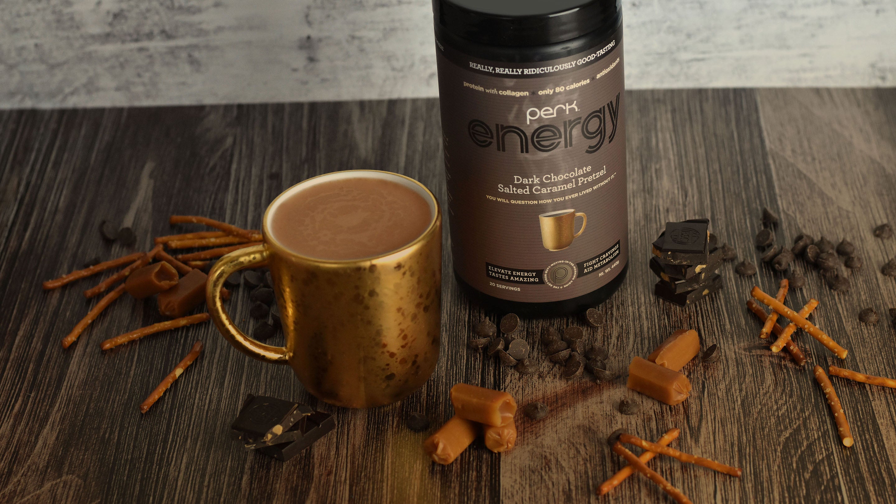 Perk Energy Dark Chocolate Salted Caramel Pretzel canister next to a cup of the drink