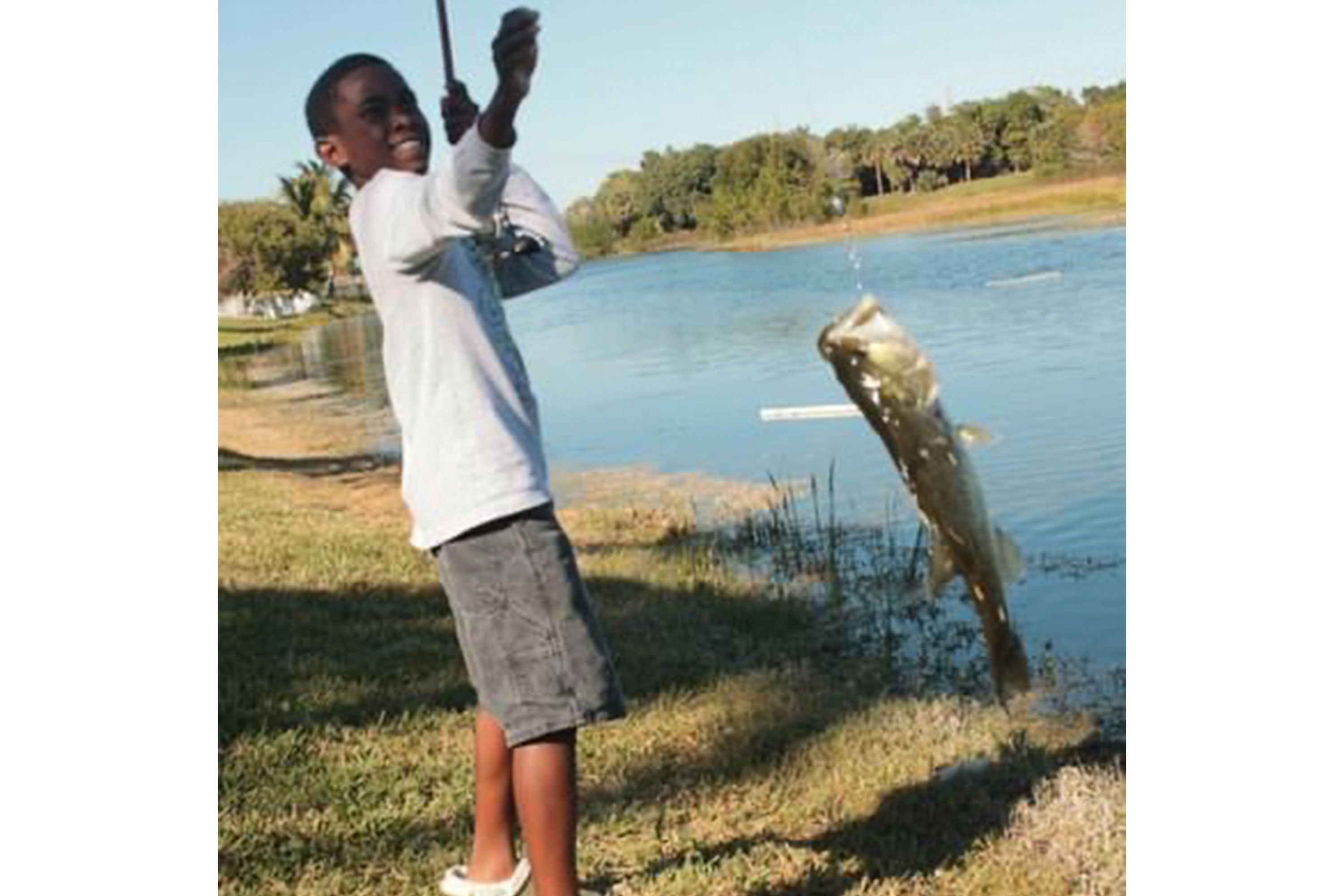 Emmanuel Williams reeling in a large fish from a lake