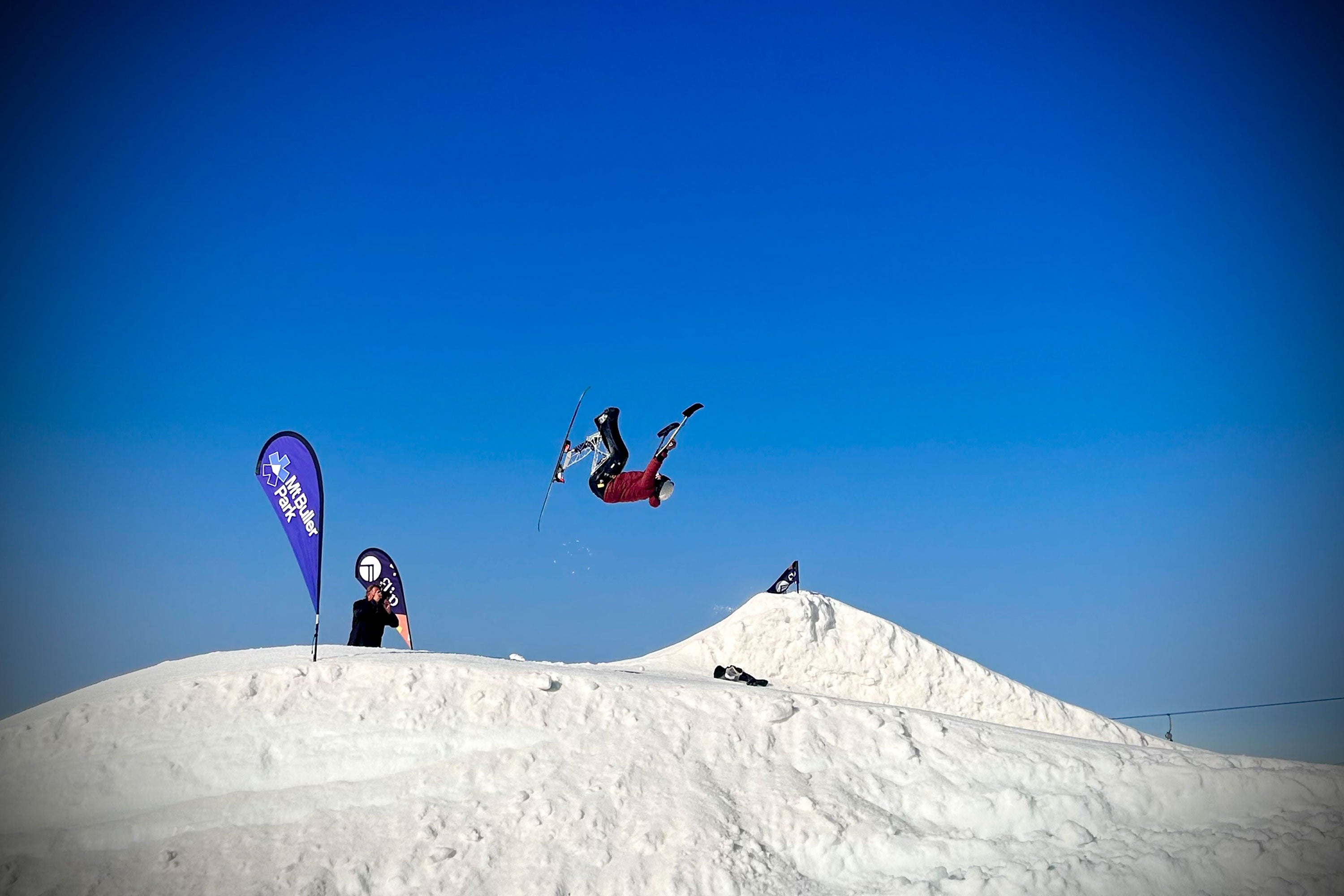 Trevor Kennison in the middle of a back flip while skiing, with blue sky behind