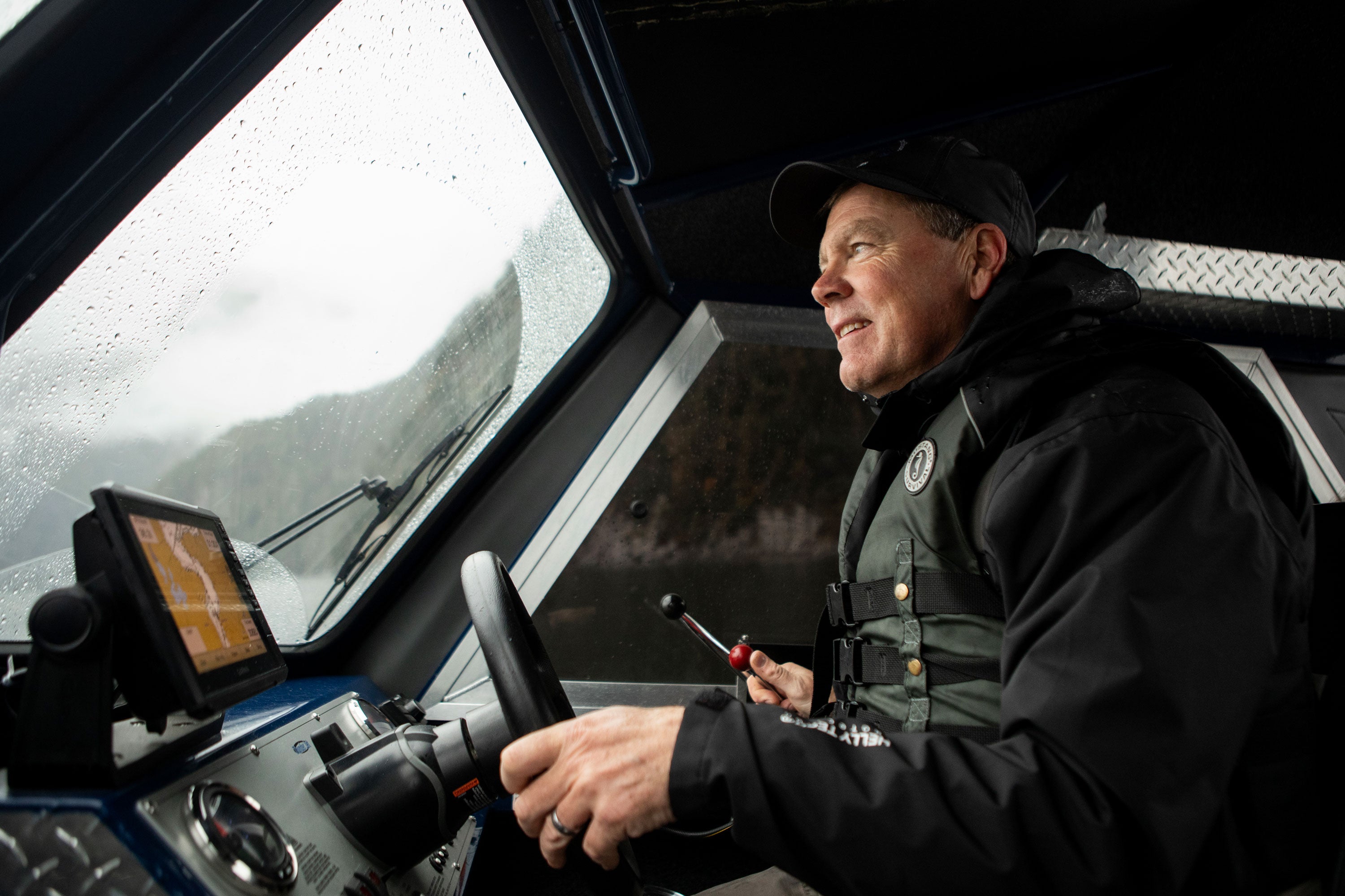 A boat skipper driving a boat, wearing waterproof clothing