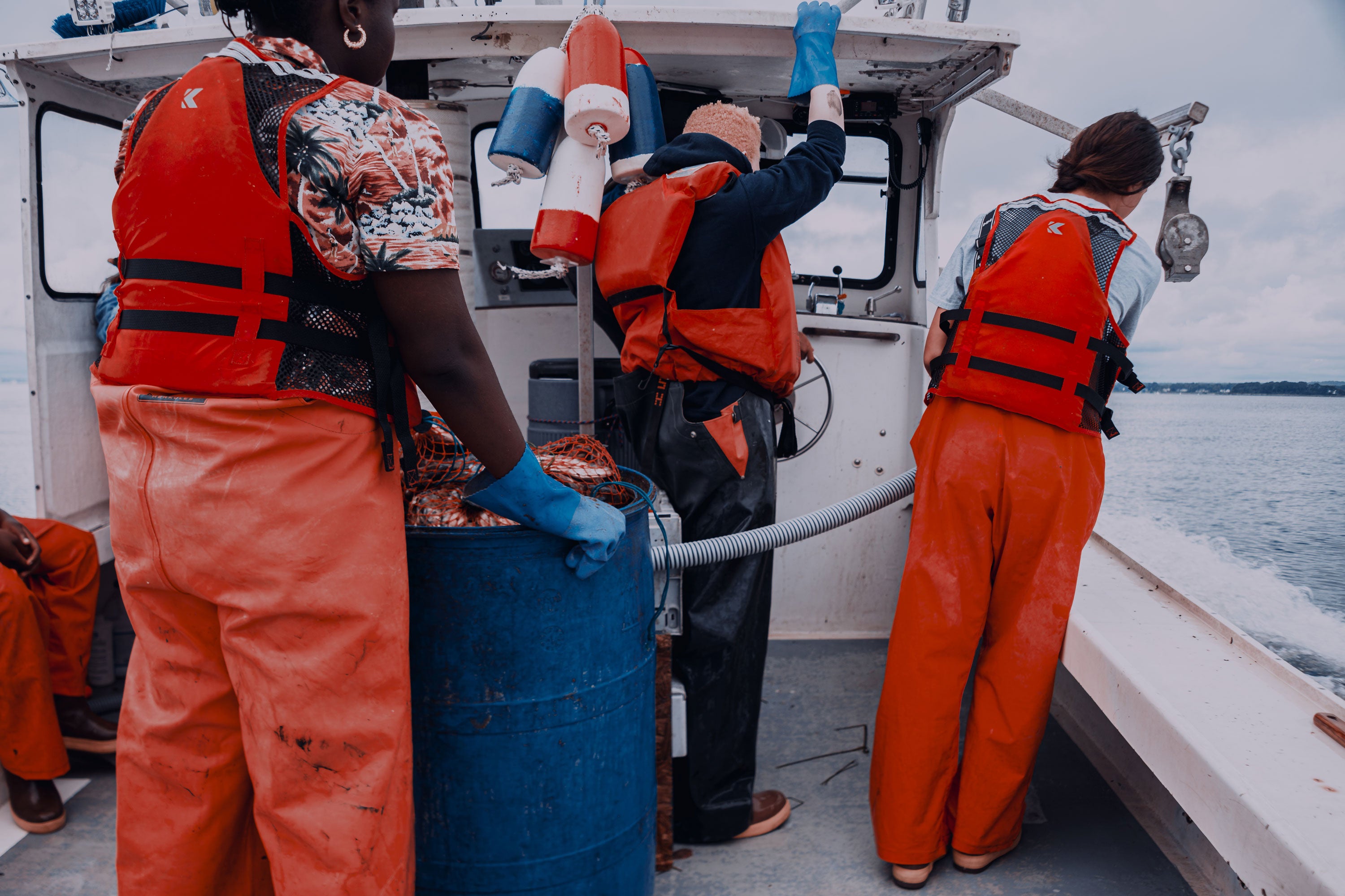 Students aboard a boat, wearing orange coveralls and life jackets