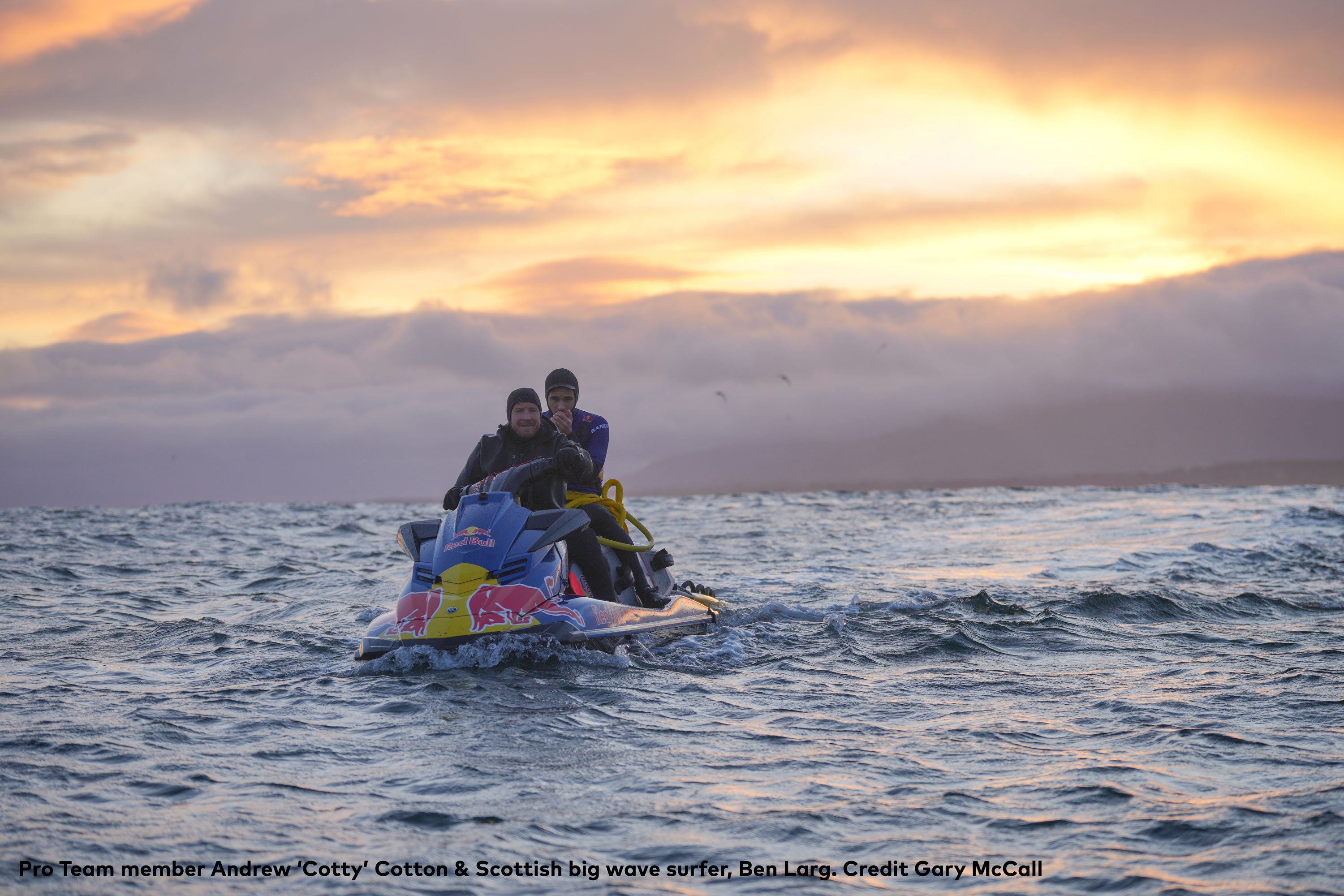 Pro Team member Andrew ‘Cotty’ Cotton & Scottish big wave surfer, Ben Larg on a jet ski close to the coast with the sun setting behind a cloudy sky behind