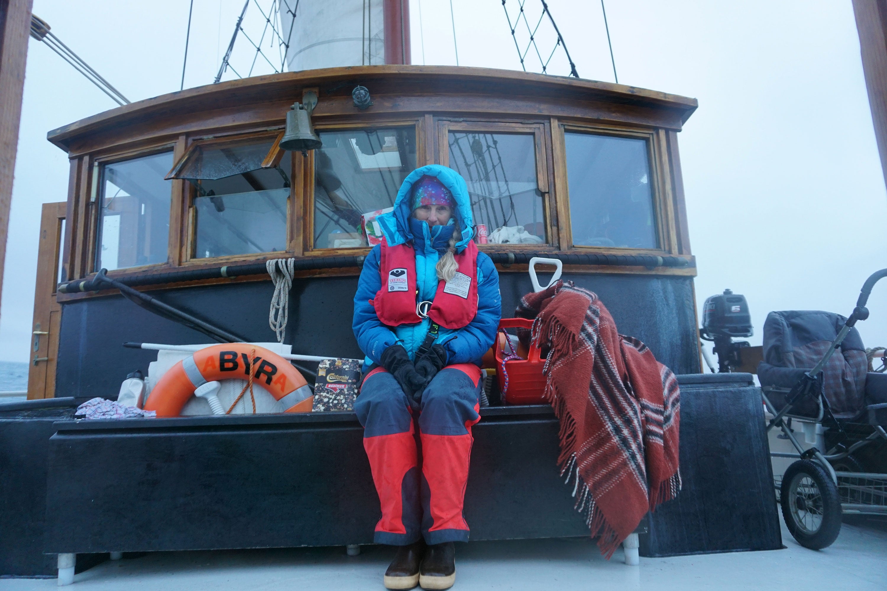 McKenna Peterson sat on the deck of a boat wearing a thick, blue coat, red life jacket, gloves, red trousers and a pair of Xtratuf Legacy Boots