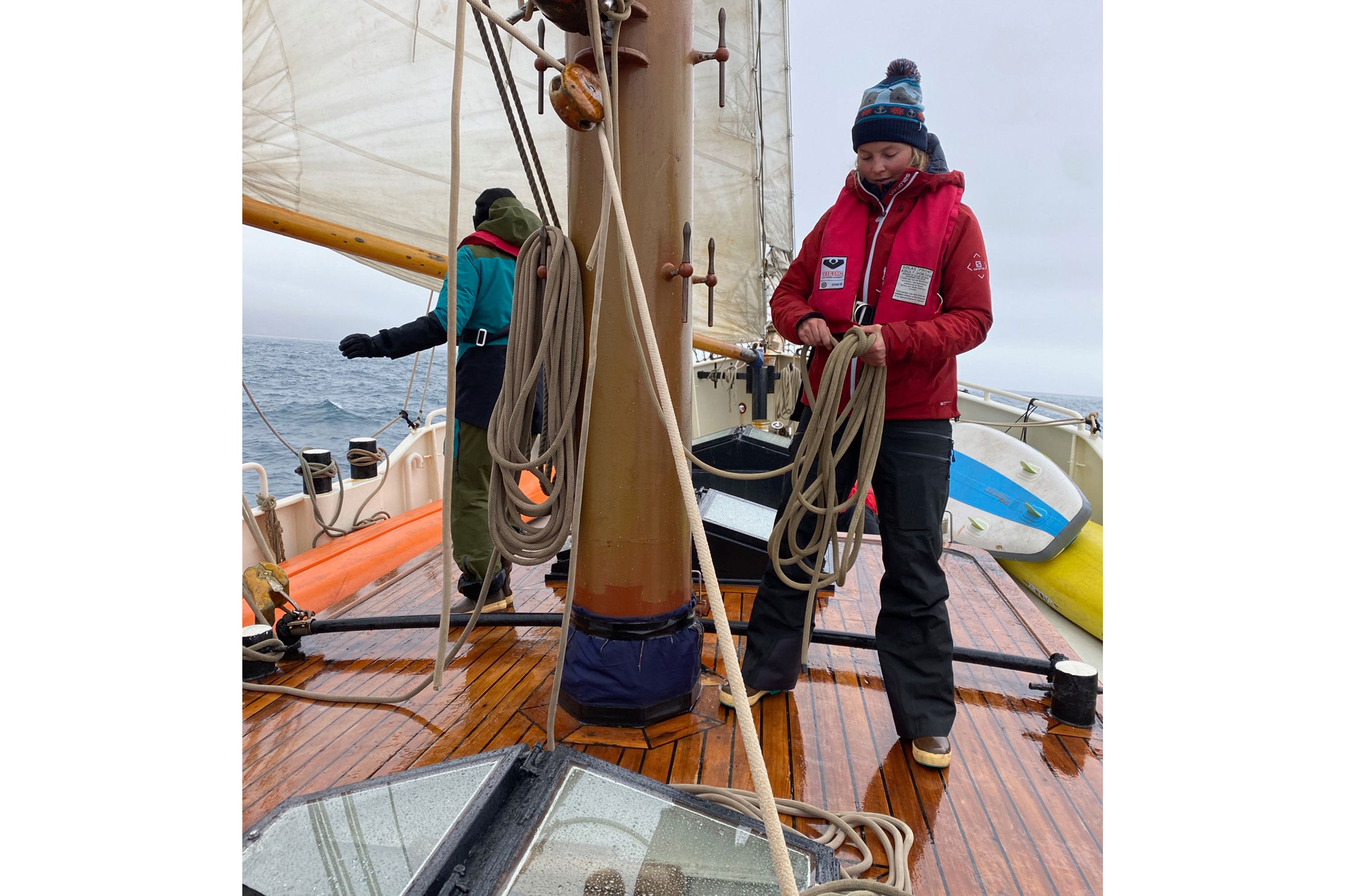 McKenna Peterson and another family member sorting through rope for the sails on their boat. McKenna is wearing a bobble hat, red jacket, life jacket, black trousers and a pair of Xtratuf Legacy Boots
