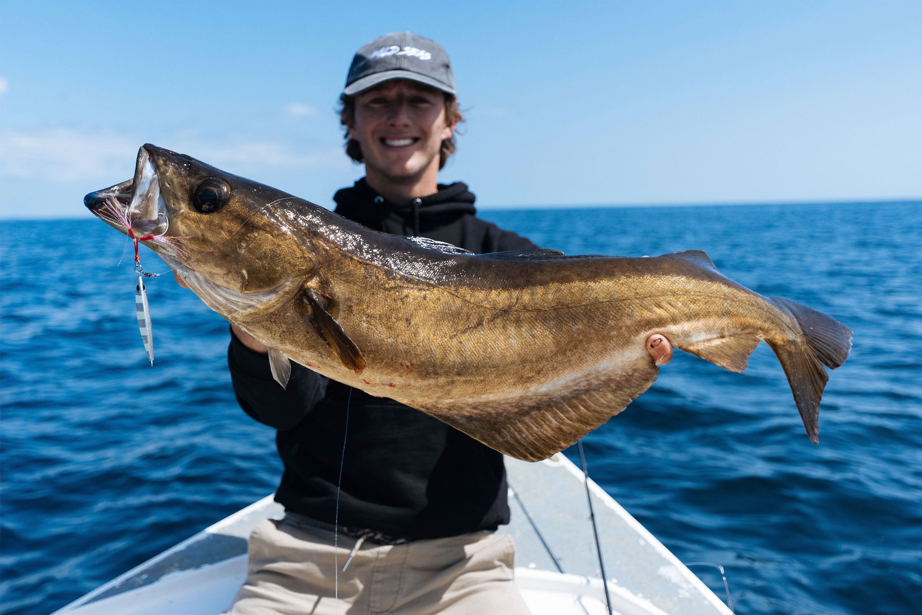 Kieren sat on a boat with a large fish that he's caught