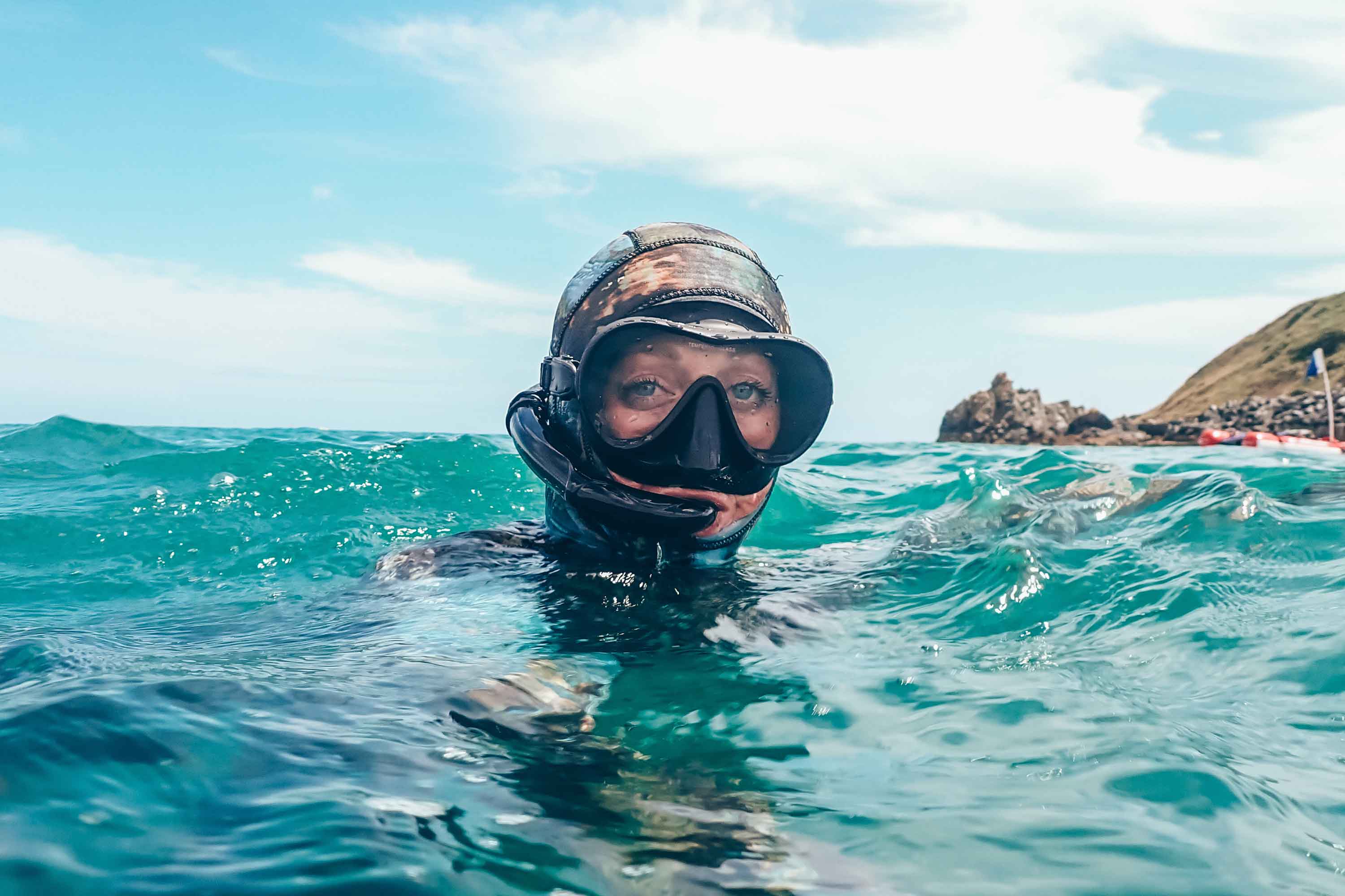 Woman with her head out of the water wearing a scuba mask and snorkel