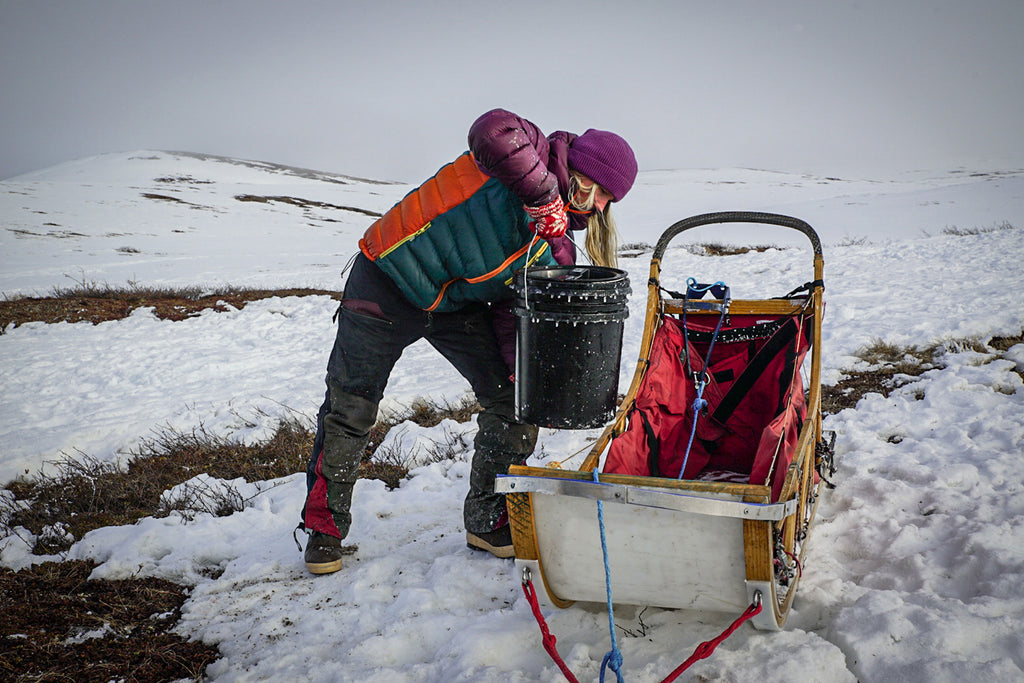 Tonje lifting a bucket over her sled