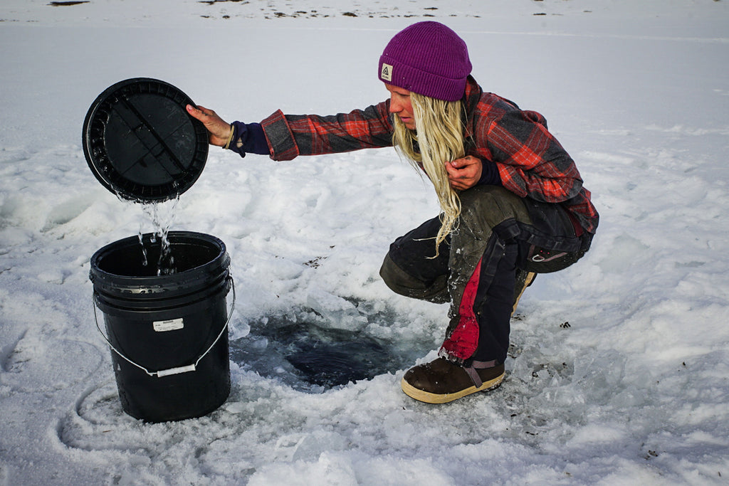 Tonje pouring water out of a hole in the ice into a bucket