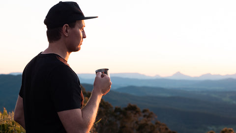 Guy holding a cup of coffee in front of a serene background in Australia