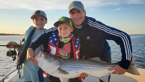 Fishing Guide with kids holding a striped bass.
