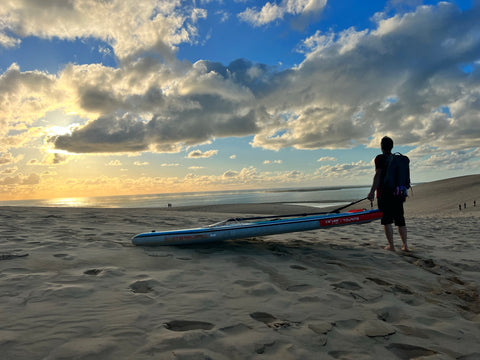 Man standing on beach with paddleboard