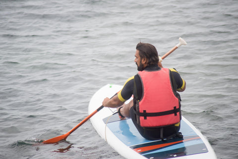 man paddleboarding wearing a buoyancy aid