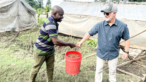Tanzania Farmer passing a bucket of raw cocoa beans to Shawn Askinosie