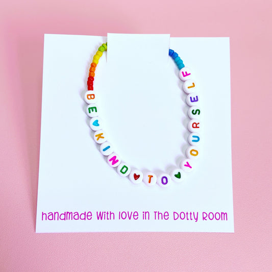 A Be Kind To Yourself rainbow bead bracelet on a white backing card which reads 'handmade with love in The Dotty Room'