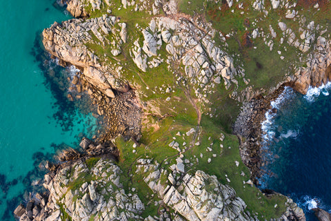 Top down view of tourquoise sea in Cornwall either side of a spit of land in sunshine