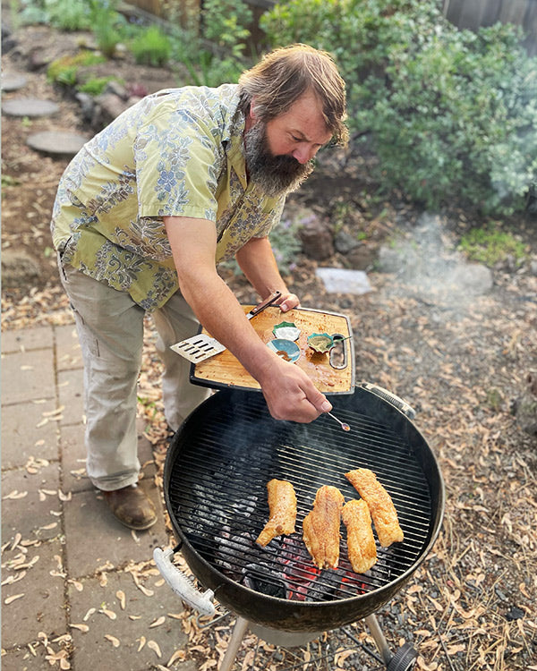 Rob grilling cod with spices on a lump charcoal grill 