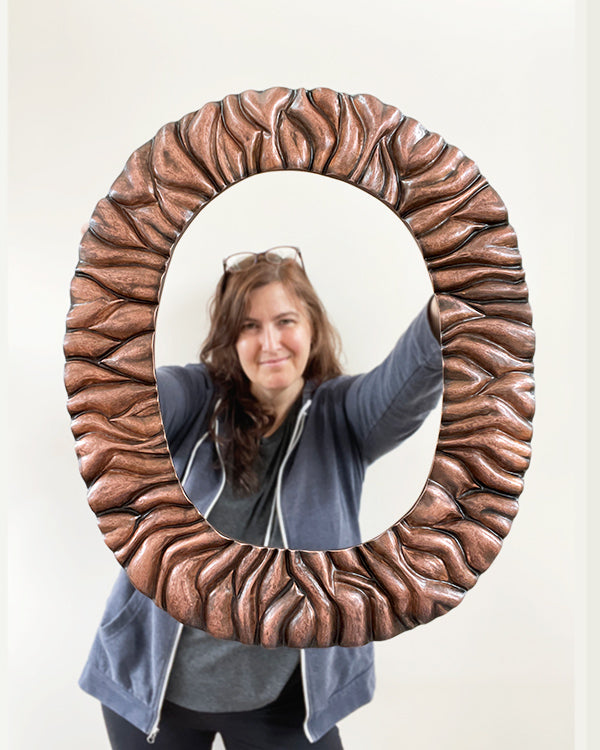 Catherine Grisez holding up hammered copper mirror frame before it gets inset with glass mirror