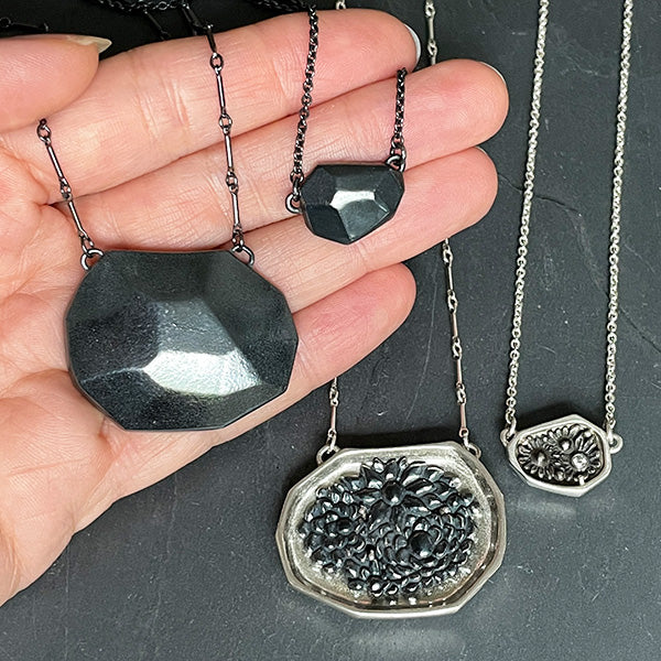 small and large versions of the Strength Rock reversible necklace in polished and darkened sterling silver, handmade in Seattle by artist Catherine Grisez