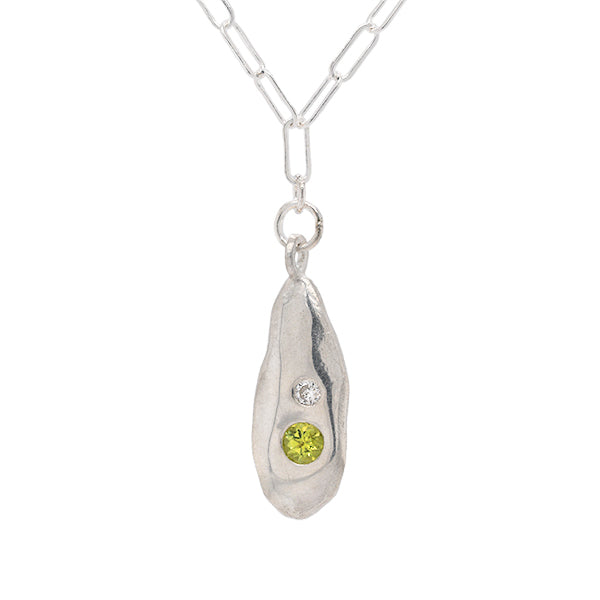 This is an image of a sterling silver necklace with two stones encrusted into the necklace.  The peridot is bigger than the recycled diamond and the recycled diamond sits over the top of the peridot jewel. 