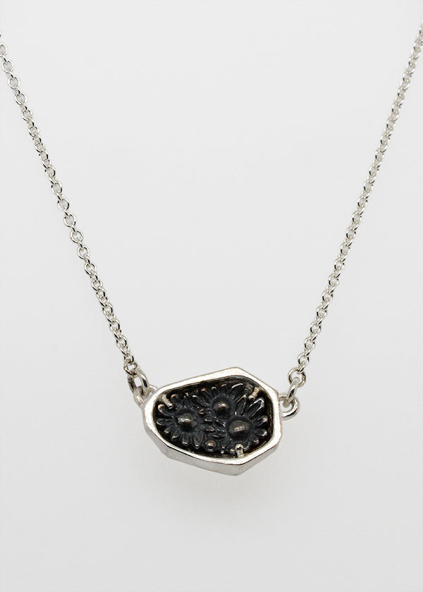 silver rock with darkened flower bloom, a necklace to symbolize strength and inner beauty handmade by artist Catherine Grisez