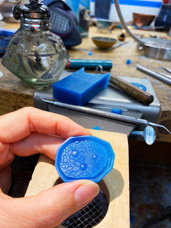 hand carved wax rock and flowers to be cast in silver for sustainable necklace symbolizing strength, handmade in Seattle