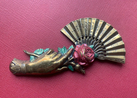 brass hand with open fan and enamelled rose