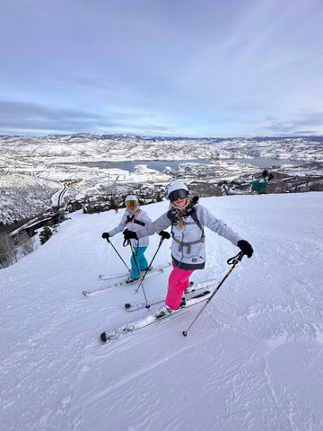 Two women skiing at Deer Valley Resort, Utah. They are on the side of the mountain smiling at the camera.