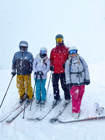 Group of four people standing on the top of a mountain at Park City, Utah. It is dumping snow.