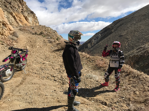 A man and a woman standing in a steep canyon next to their dirt bikes in Jawbone